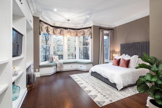 Stylish master bedroom with a plush upholstered bed, layered bedding, soft lighting, and modern décor for a cozy and elegant retreat.